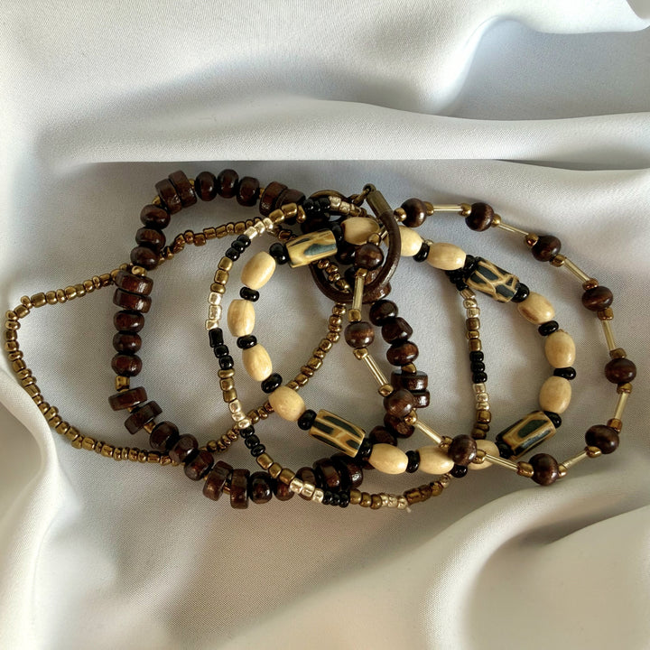 Five-strand beaded bracelet shown spread out, highlighting layered wood, glass, and polymer clay bead design.