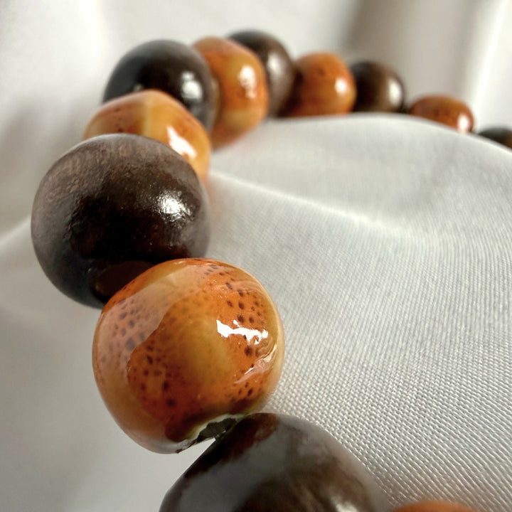 Ceramic and wood beaded bracelet arranged on white background from angled view