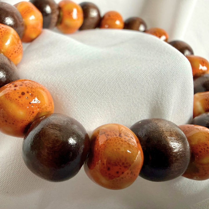 Side angle view of ceramic and wood beaded bracelet in brown tones
