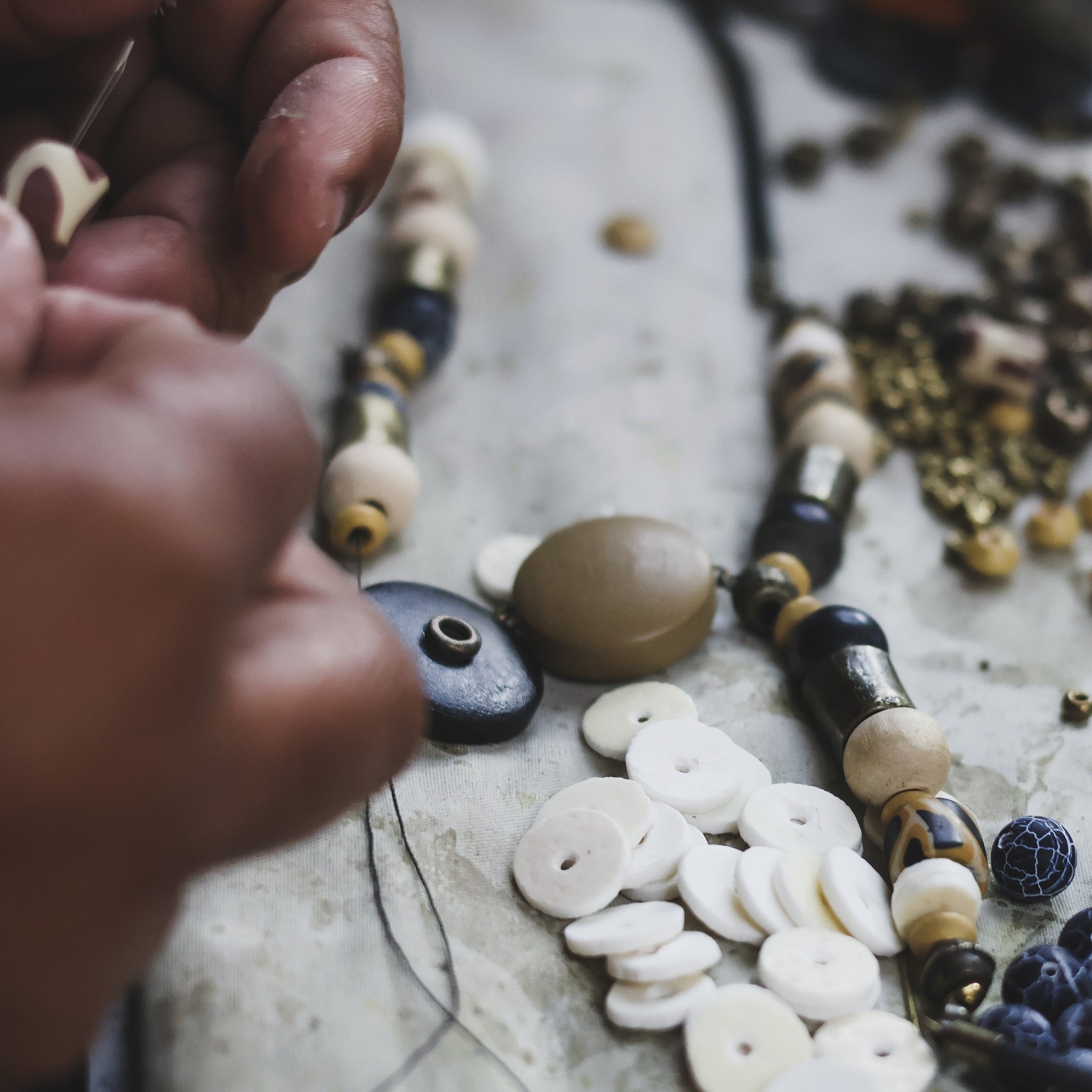 Close-up of hands working with black and brown beads during jewellery making.