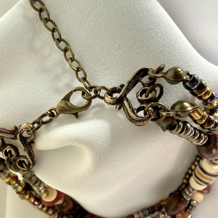 Close-up of the adjustable antique brass clasp and chain on a handcrafted multi-strand African beaded bracelet.