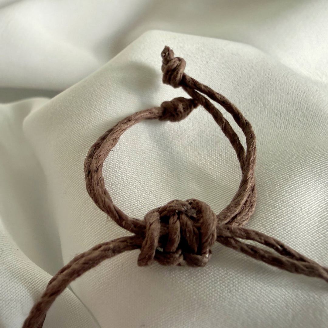 Adjustable hemp cord closure detail on a handcrafted ceramic bead bracelet.