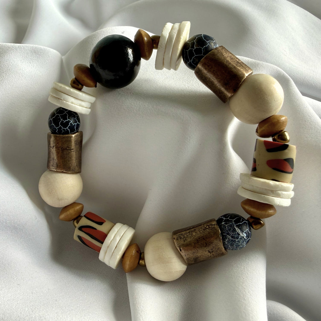 Top view of a handcrafted bracelet featuring crackle agate gemstones, wood beads, and antique brass accent beads arranged in a full circular layout.