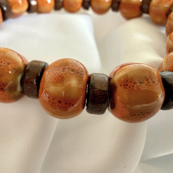 Angled close-up of a handcrafted bracelet highlighting the texture contrast between ceramic and flat wood beads.