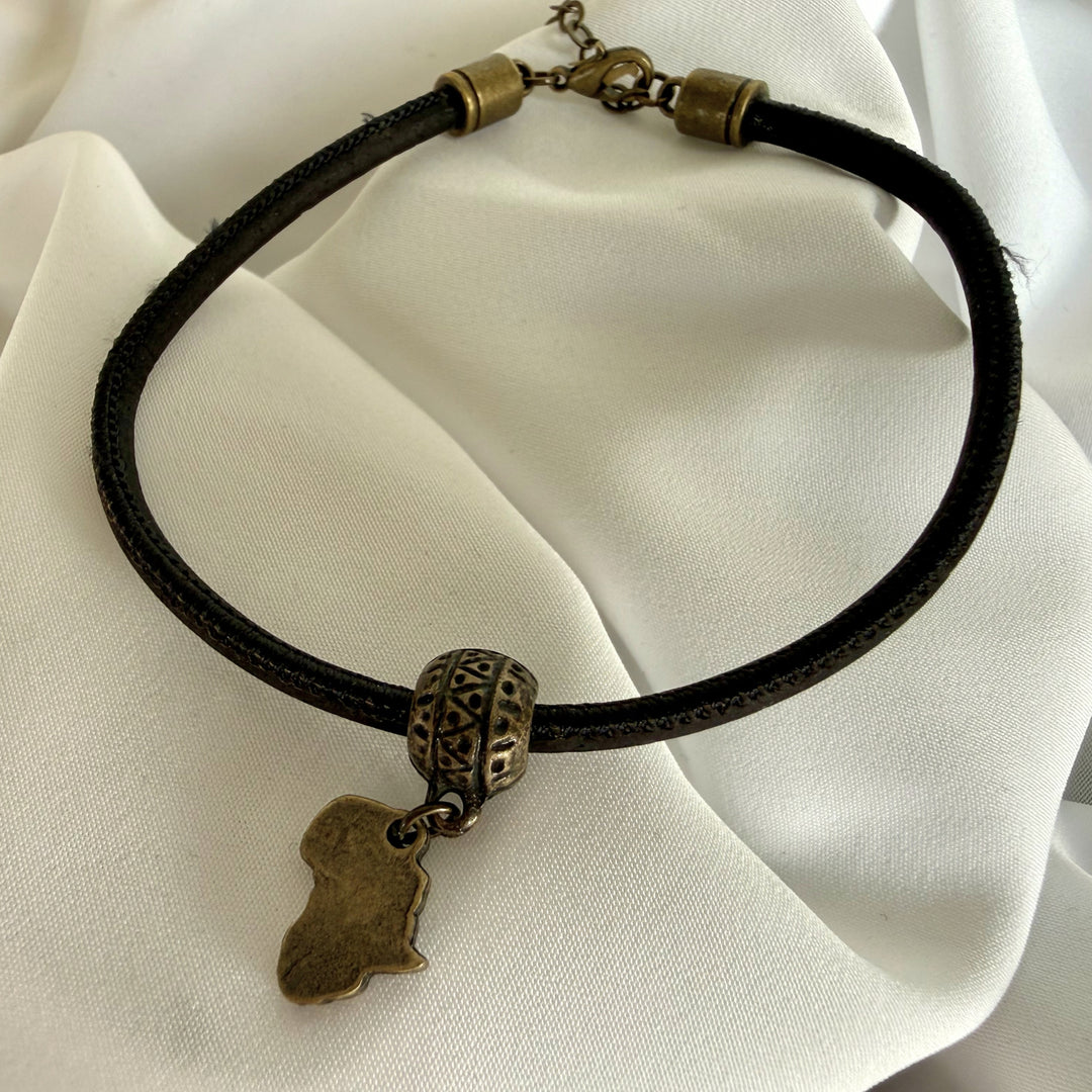 Full view of a handcrafted black cork bracelet with antique brass Africa charm and stainless steel clasp.