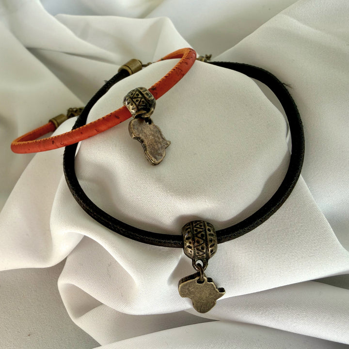 Close-up of antique brass Africa charm featured on handcrafted black and red cork bracelets.