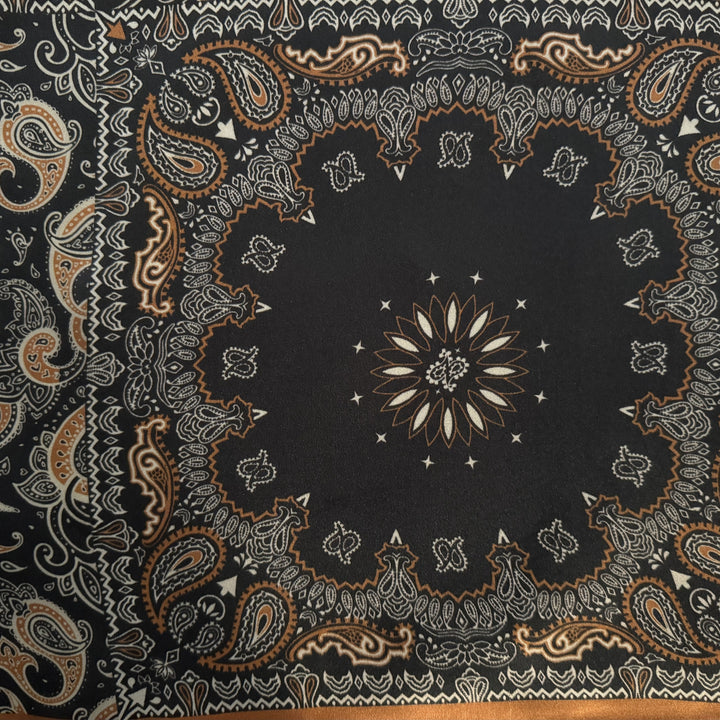 Close-up of paisley and floral motifs on black and copper silk fabric.