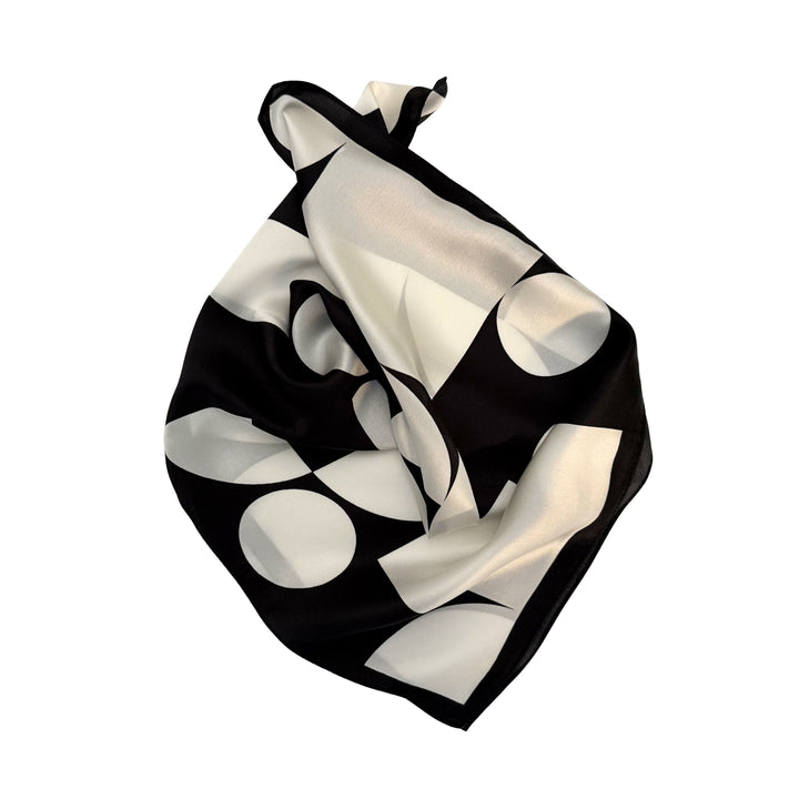 Geometric silk scarf neatly folded showing black and ivory pattern design.