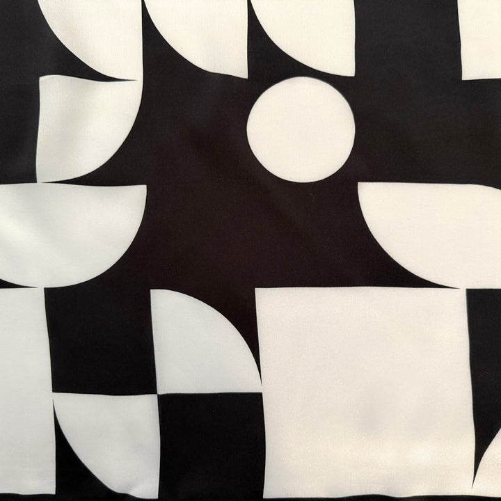 Close-up of black and white geometric circles and squares on silk fabric.