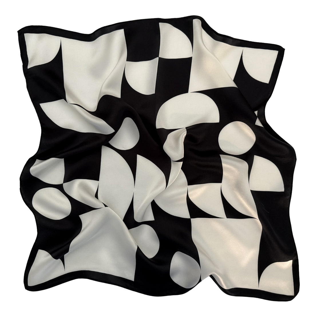 Black and ivory geometric silk scarf softly laid out in a relaxed flat arrangement.