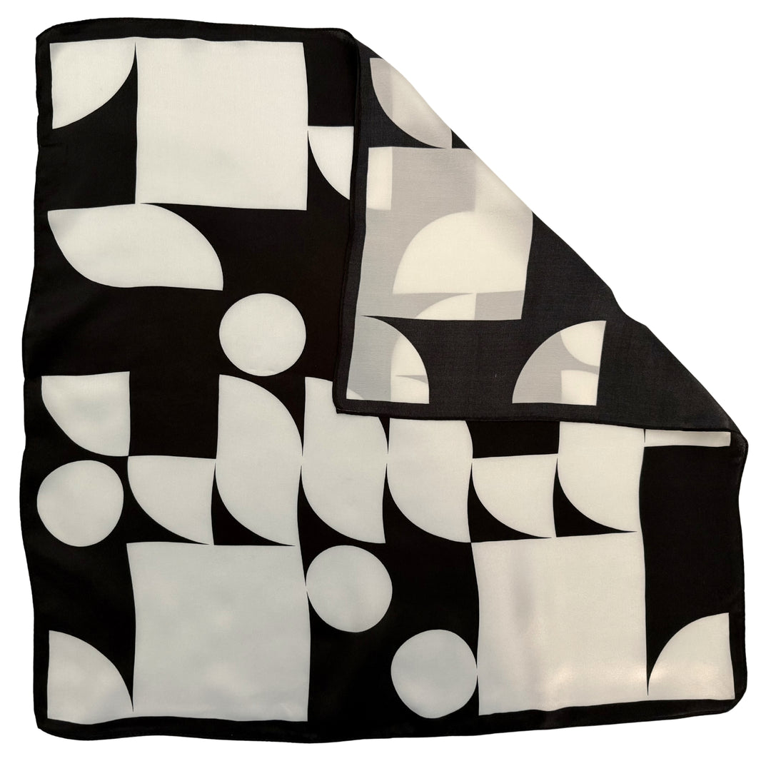 Geometric silk scarf with folded corner showing reverse side and one-sided print.