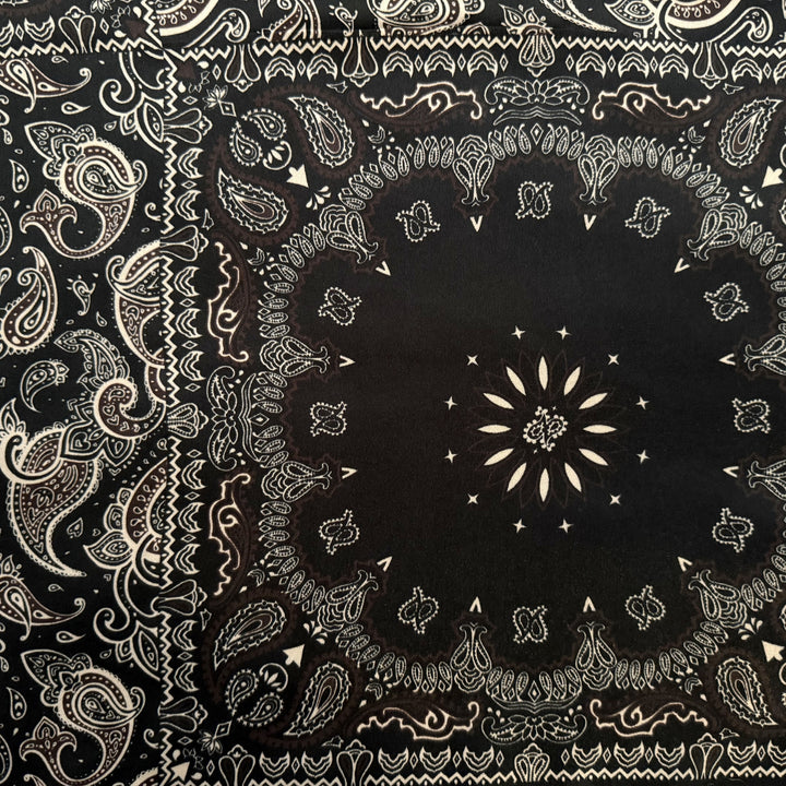 Close-up of black floral and paisley pattern in brown and beige tones on silk fabric.
