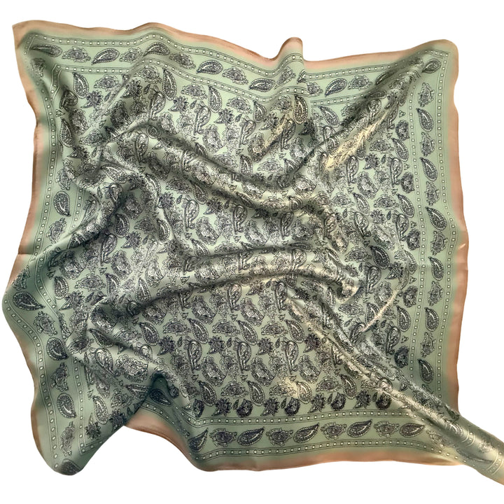 Black, white and green paisley silk scarf softly laid out in a relaxed arrangement.