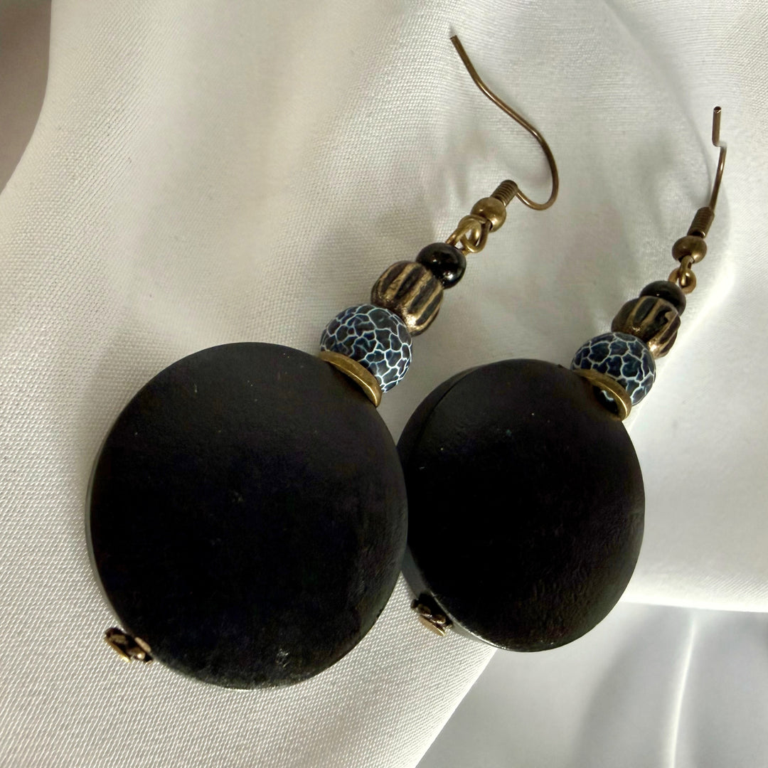Top view of handcrafted drop earrings placed side by side featuring black wood and crackle agate beads.