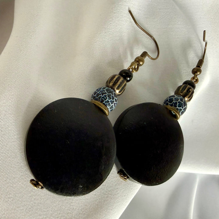 Top view of handcrafted drop earrings placed side by side featuring black wood and crackle agate beads.
