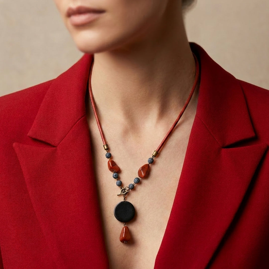 Handcrafted black wood and red jasper pendant necklace worn by a woman with a red blazer.