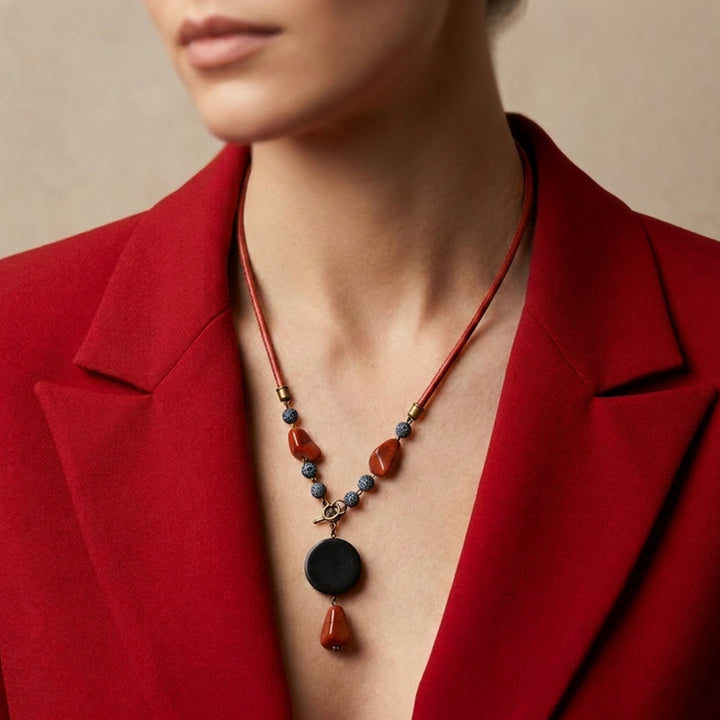 Handcrafted black wood and red jasper pendant necklace worn by a woman with a red blazer.