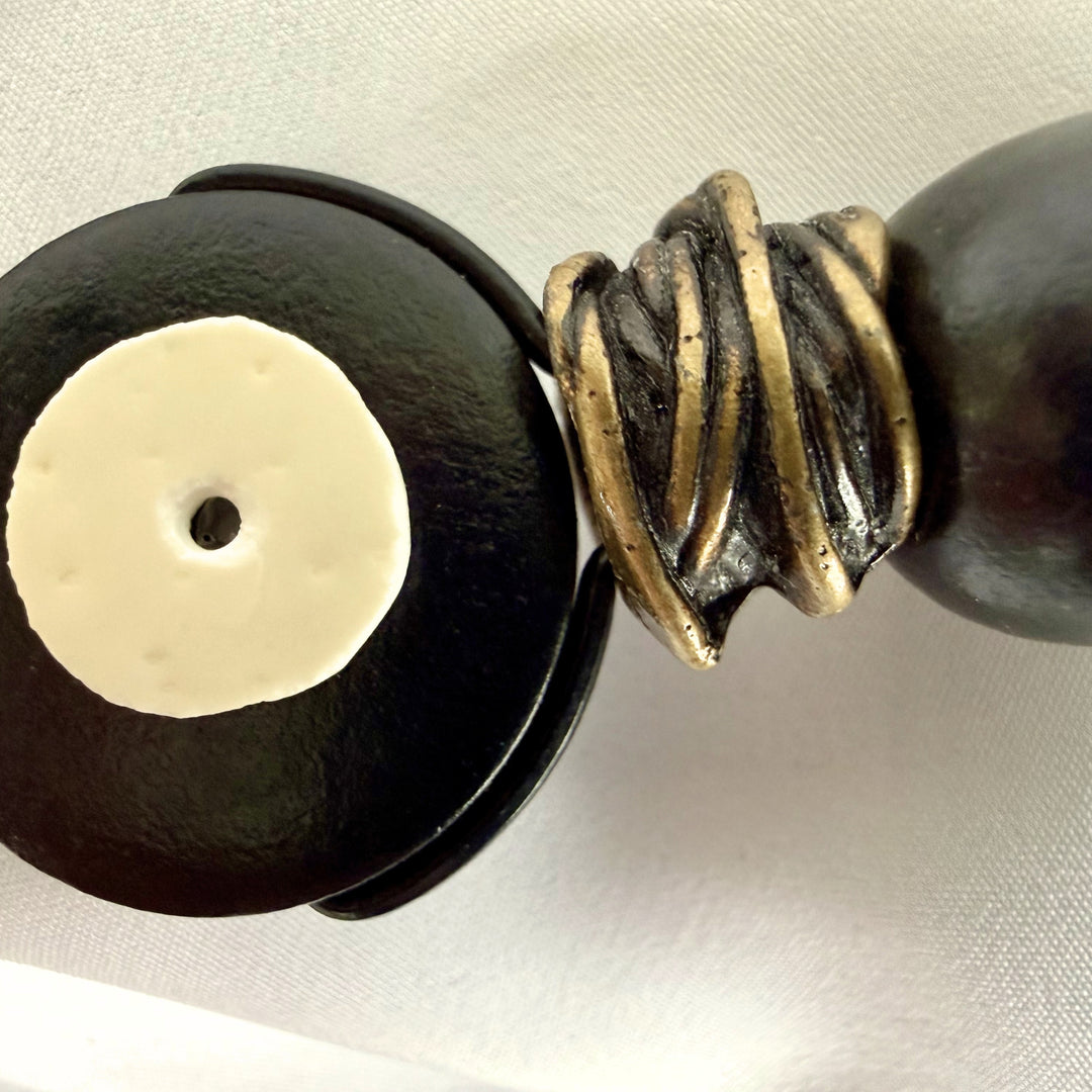 Angled view of handmade black wooden pendant necklace with eggshell inlay