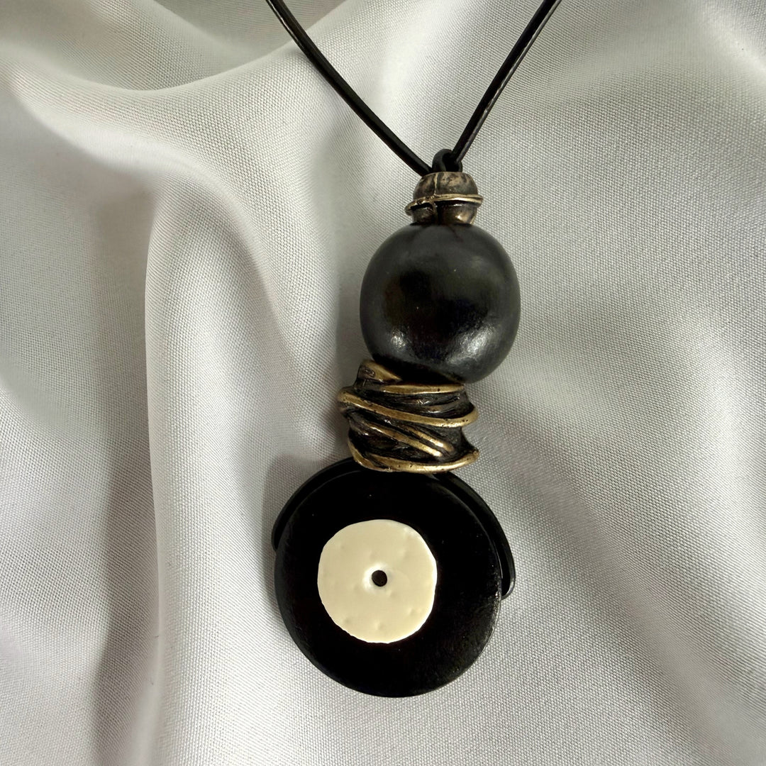 Detail of handmade black wooden pendant necklace with eggshell inlay