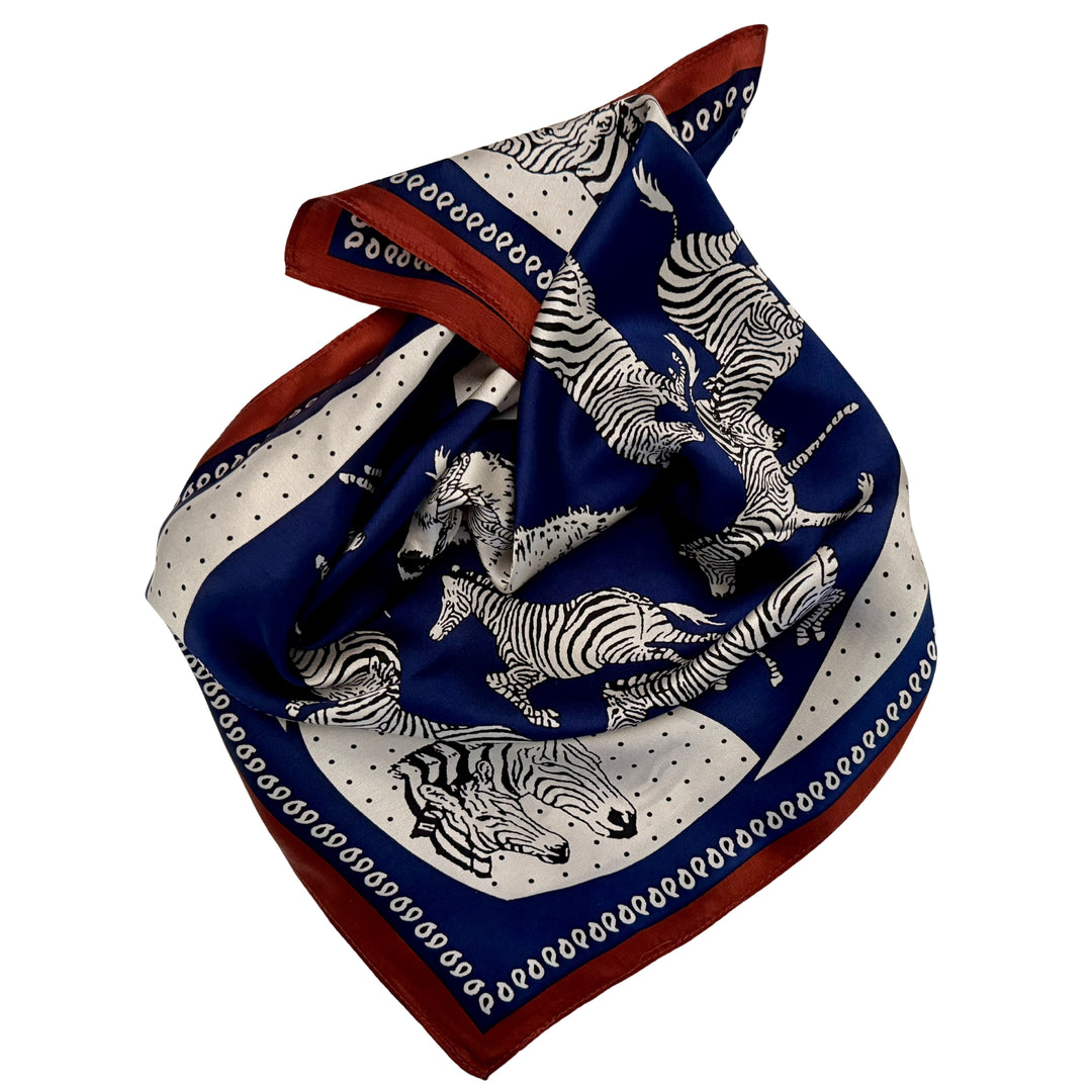 Blue and white zebra silk scarf neatly folded showing the design and copper border.