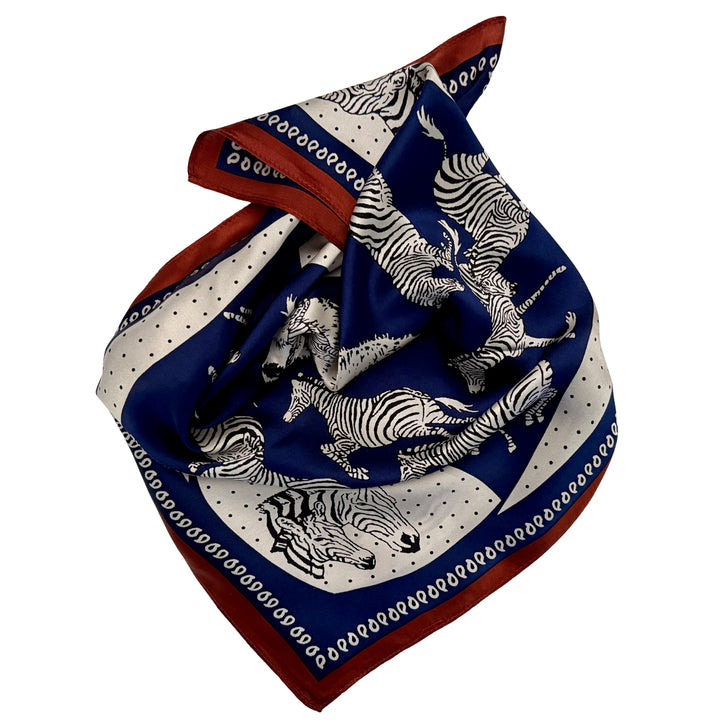 Blue and white zebra silk scarf neatly folded showing the design and copper border.