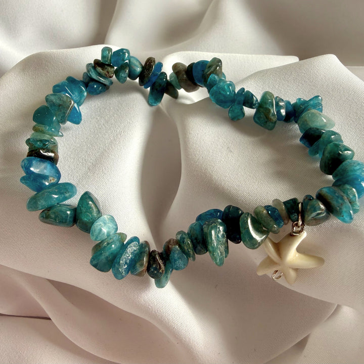 Full view of a handcrafted blue semi-precious chip bead bracelet with a white seastar charm.