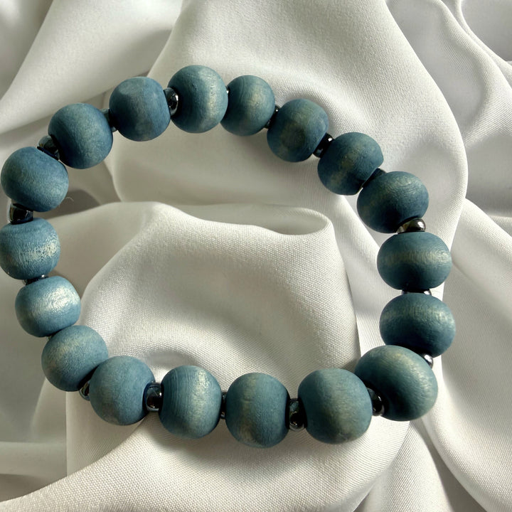 Full view of a handcrafted bracelet made with blue wood beads and silver-coloured seed beads on elastic cord.