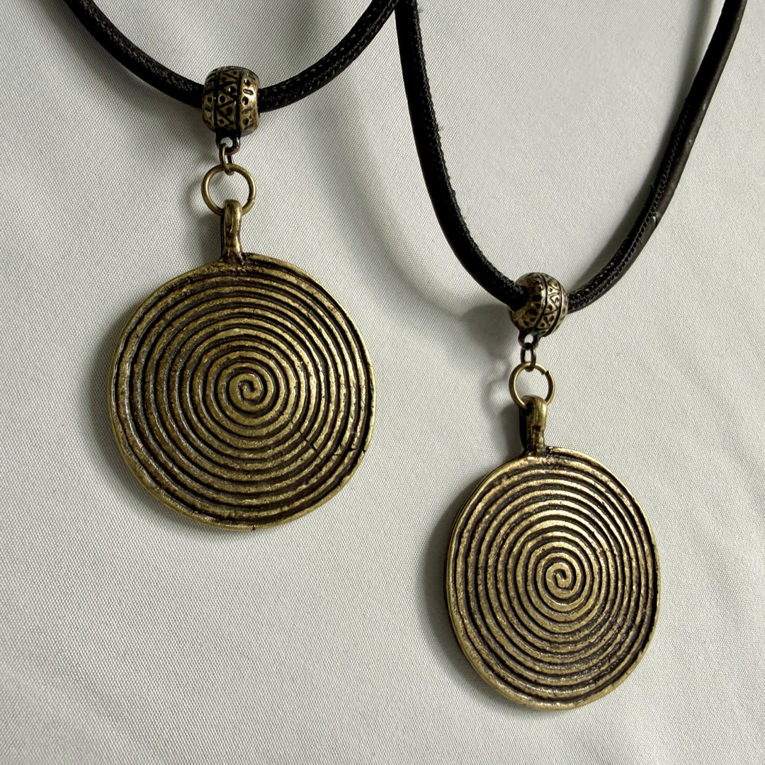Two identical handcrafted necklaces with bronze spiral charms shown side by side on black cork cord.