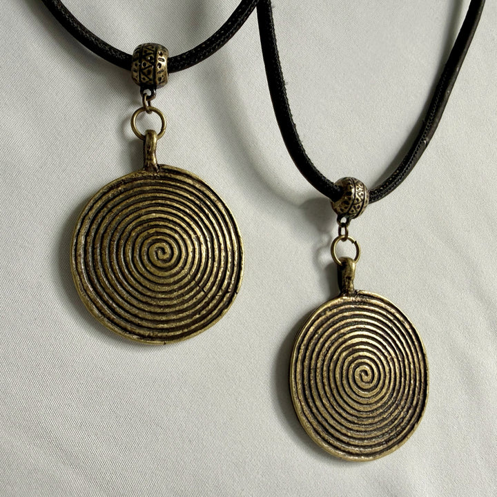 Two identical handcrafted necklaces with bronze spiral charms shown side by side on black cork cord.