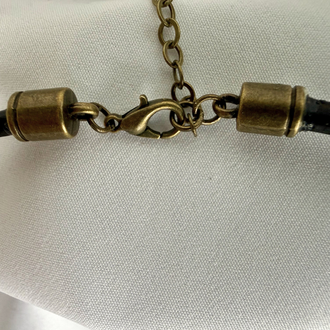 Close-up of adjustable clasp and antique brass hardware on a handcrafted bronze spiral charm necklace.