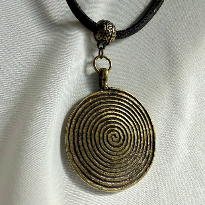 Front view of a handcrafted necklace featuring an antique bronze spiral charm on black cork cord.