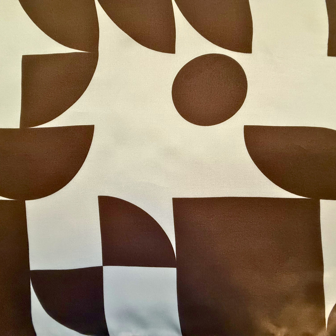 Close-up of brown circles and squares on ivory silk fabric.