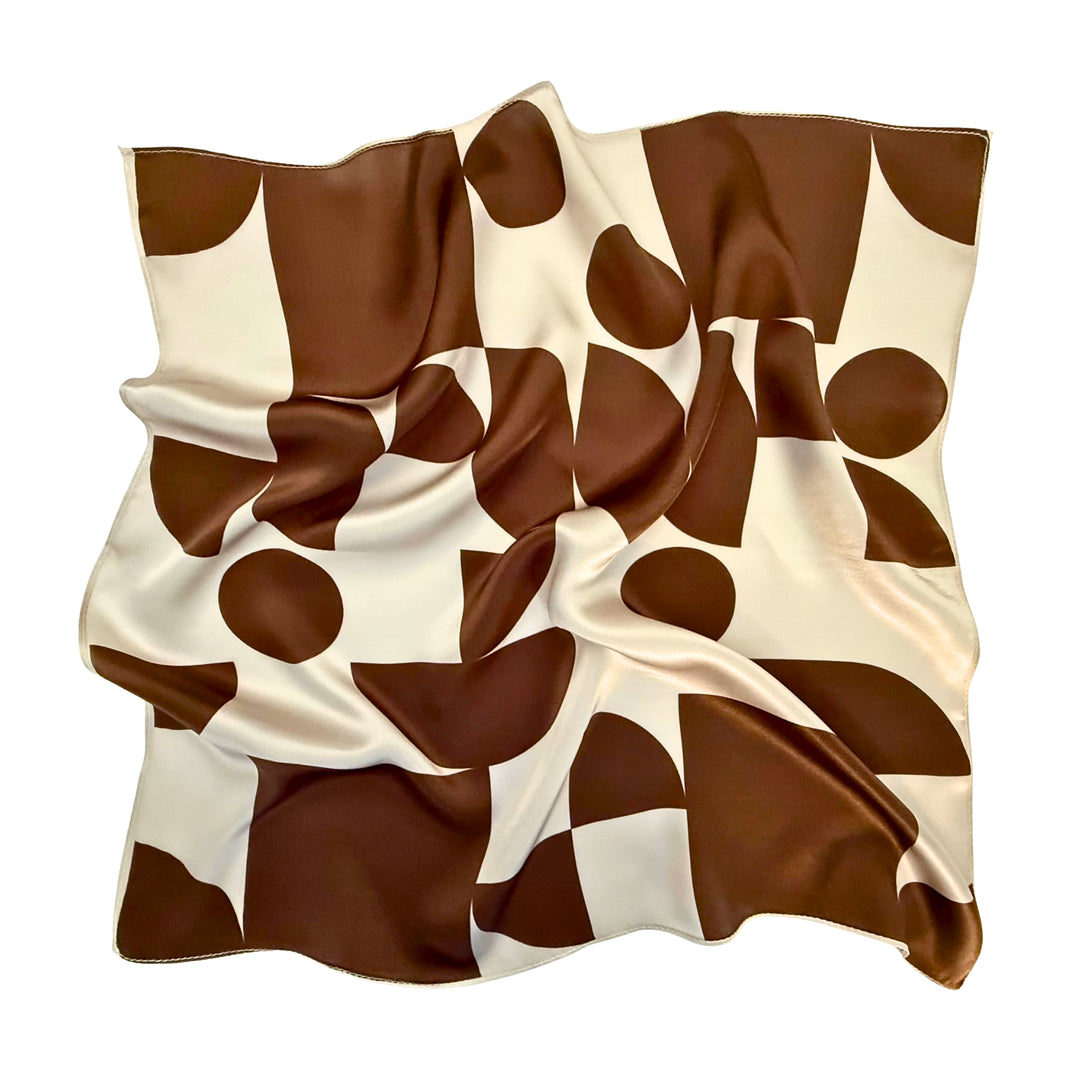 Brown geometric silk scarf softly laid out in a relaxed arrangement.