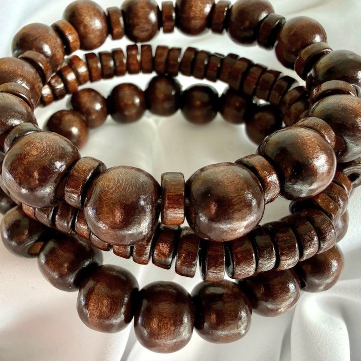 Three brown wooden beaded bracelets stacked on top of each other, showing round, flat, and mixed bead designs.