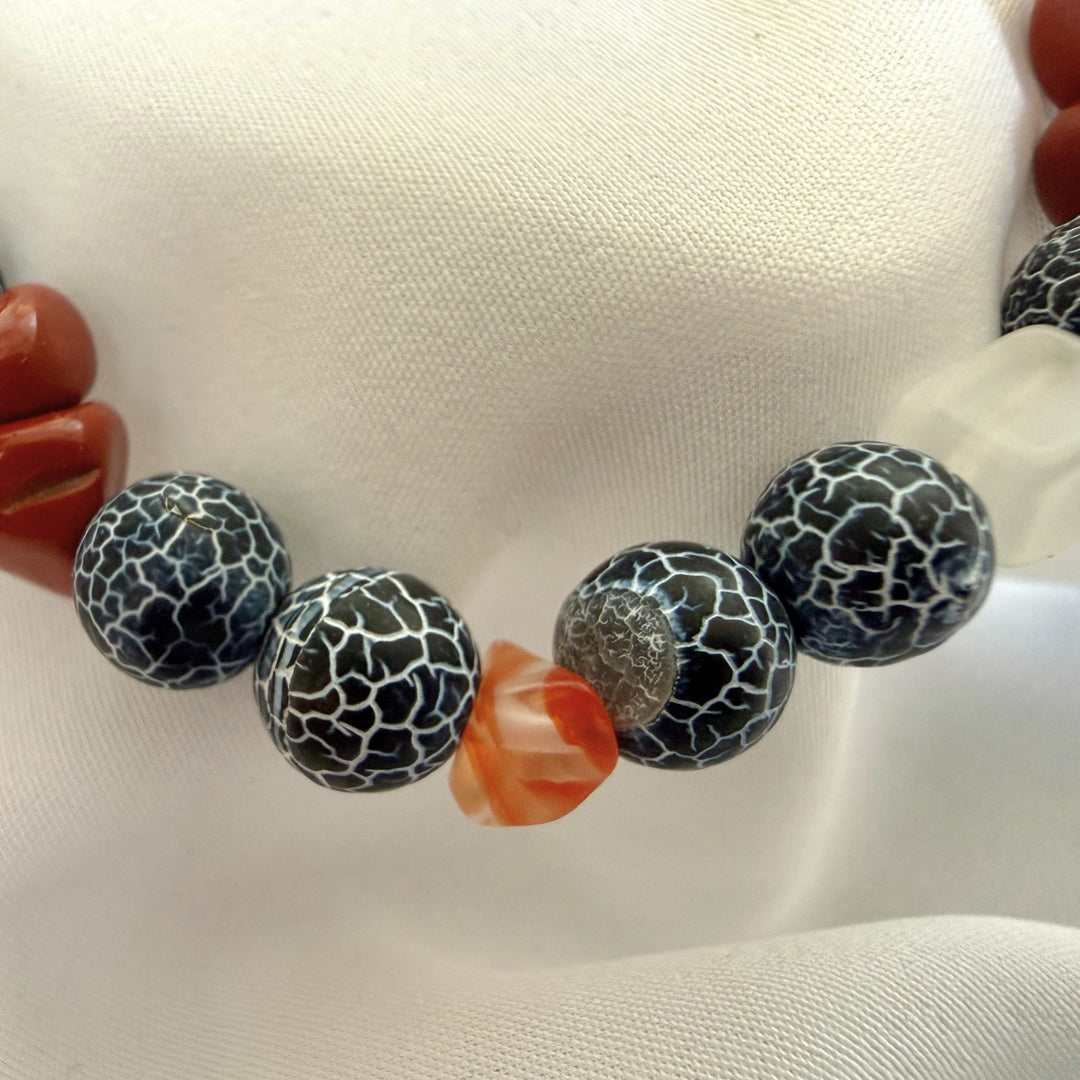 Close-up of a handcrafted bracelet showing natural carnelian chip beads paired with black crackle agate gemstones.