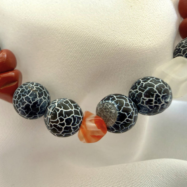 Close-up of a handcrafted bracelet showing natural carnelian chip beads paired with black crackle agate gemstones.