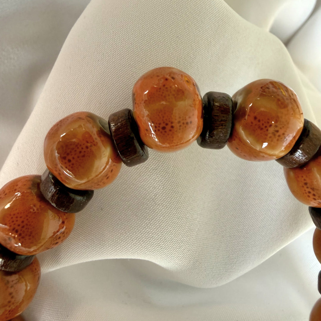 Close-up of a handcrafted bracelet showing smooth ceramic beads paired with natural flat wood beads.