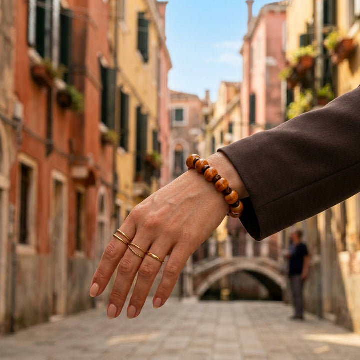 Handcrafted ceramic and flat wood beaded bracelet in light and dark brown tones worn on a woman walking through the streets of Venice.