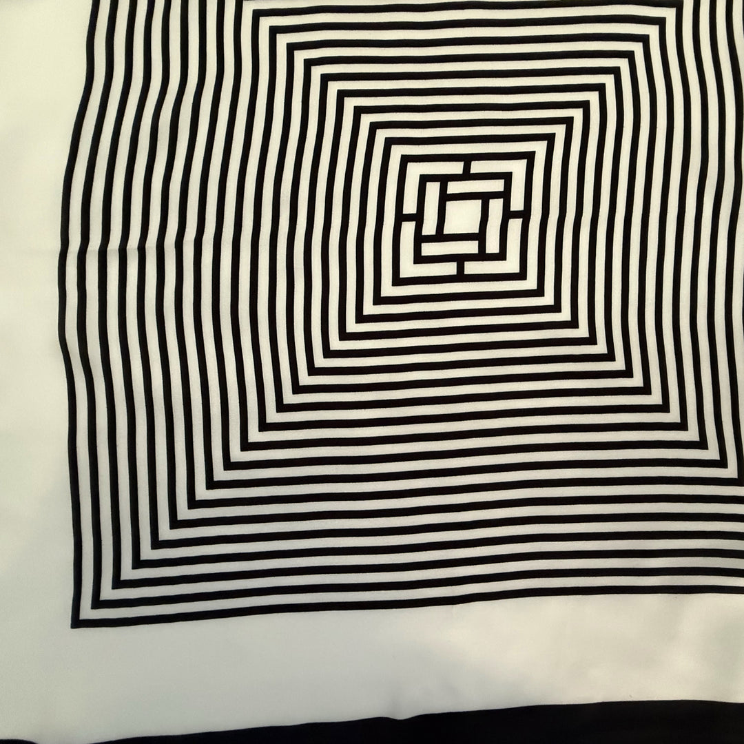 Close-up view of the intricate black and ivory labyrinth geometric pattern printed on smooth mulberry silk fabric.