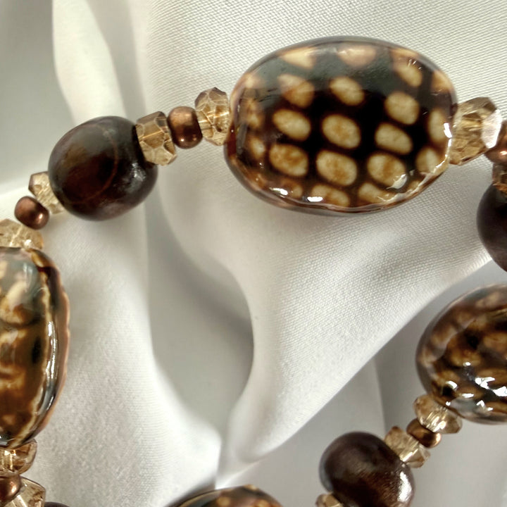 Detailed view of mixed ceramic, acrylic, glass, and wood beads with earthy tones.