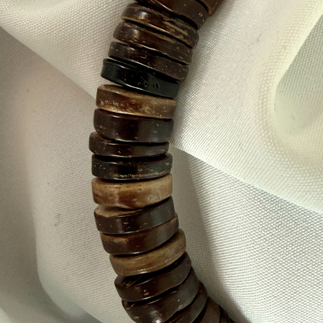 Close-up of natural brown coconut wood beads on a handcrafted elastic bracelet.