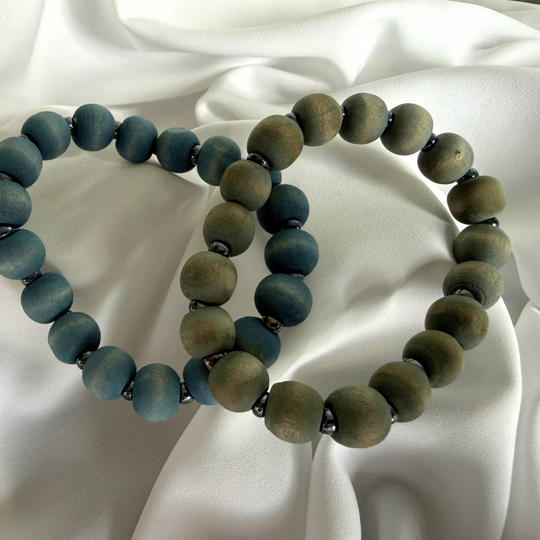 Top view of two handcrafted wood beaded bracelets in blue and grey tones with silver-coloured seed bead accents.