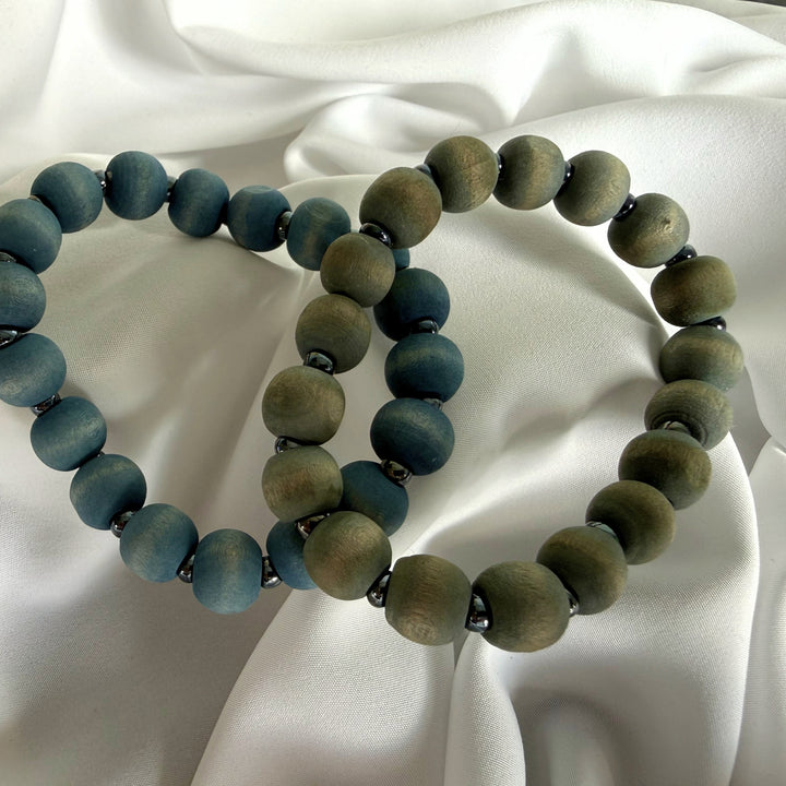 Top view of two handcrafted wood beaded bracelets in blue and grey tones with silver-coloured seed bead accents.
