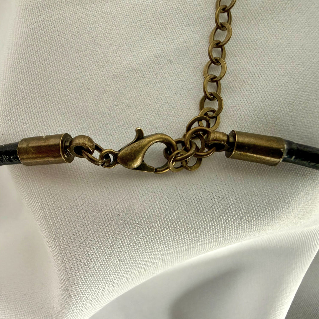 Close-up of adjustable clasp and antique brass hardware on a handcrafted copper elephant disc necklace.