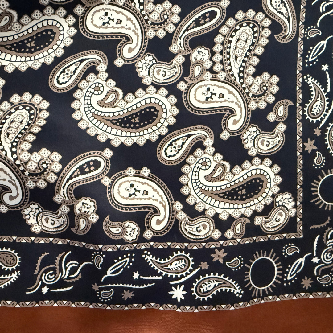 Close-up of paisley pattern on dark blue mulberry silk fabric.