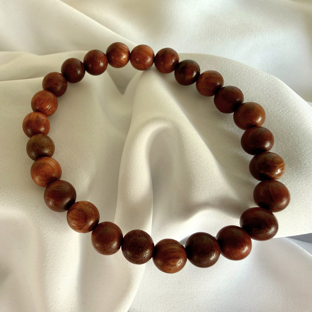Full view of a handcrafted bracelet made with dark brown wood beads on elastic cord.