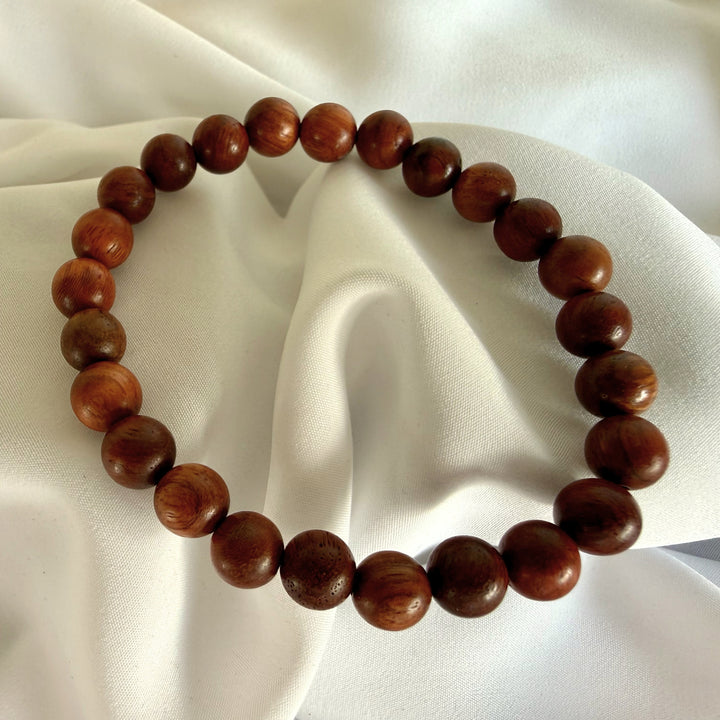 Full view of a handcrafted bracelet made with dark brown wood beads on elastic cord.