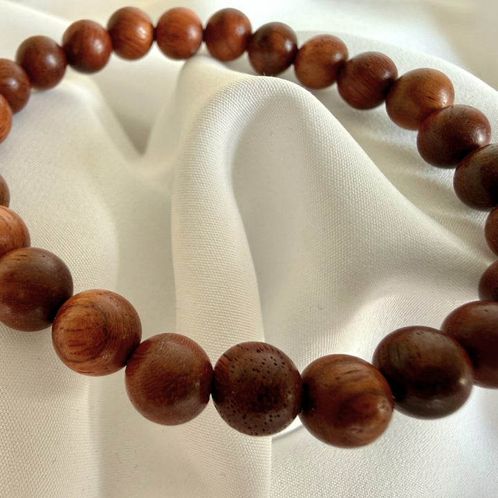 Close-up of dark brown wood beads showing natural grain texture on a handmade bracelet.