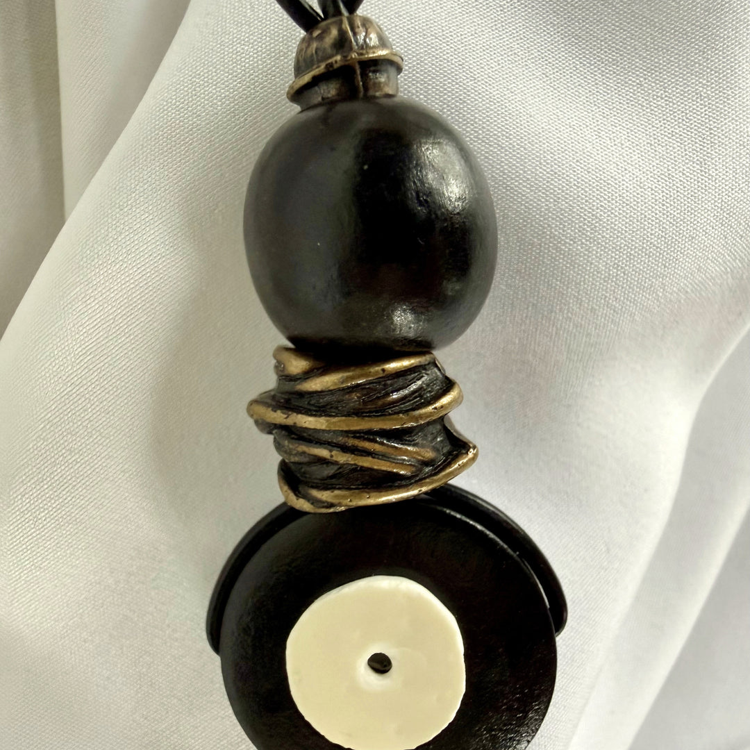 Close-up of ostrich eggshell inlay on black wooden pendant necklace
