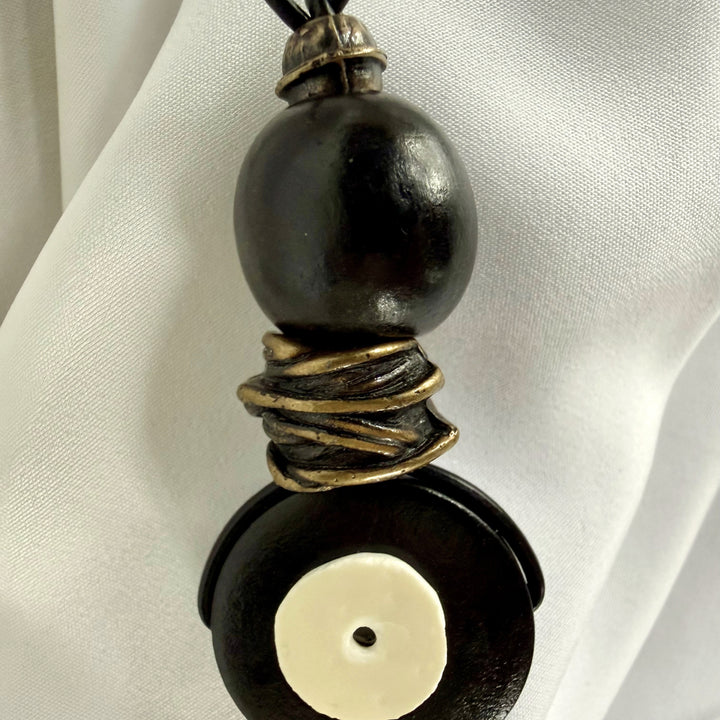 Close-up of ostrich eggshell inlay on black wooden pendant necklace